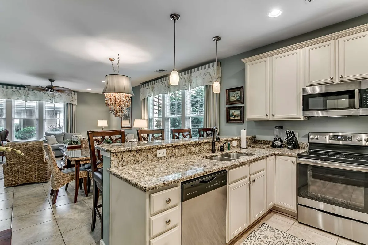 A beautifully designed kitchen and dining area, featuring granite countertops, modern appliances, pendant lighting, and large windows. The kitchen opens onto the dining space, reinforcing the home's flow and suitability for group gatherings, from cooking festive dinners to enjoying cozy breakfasts together.