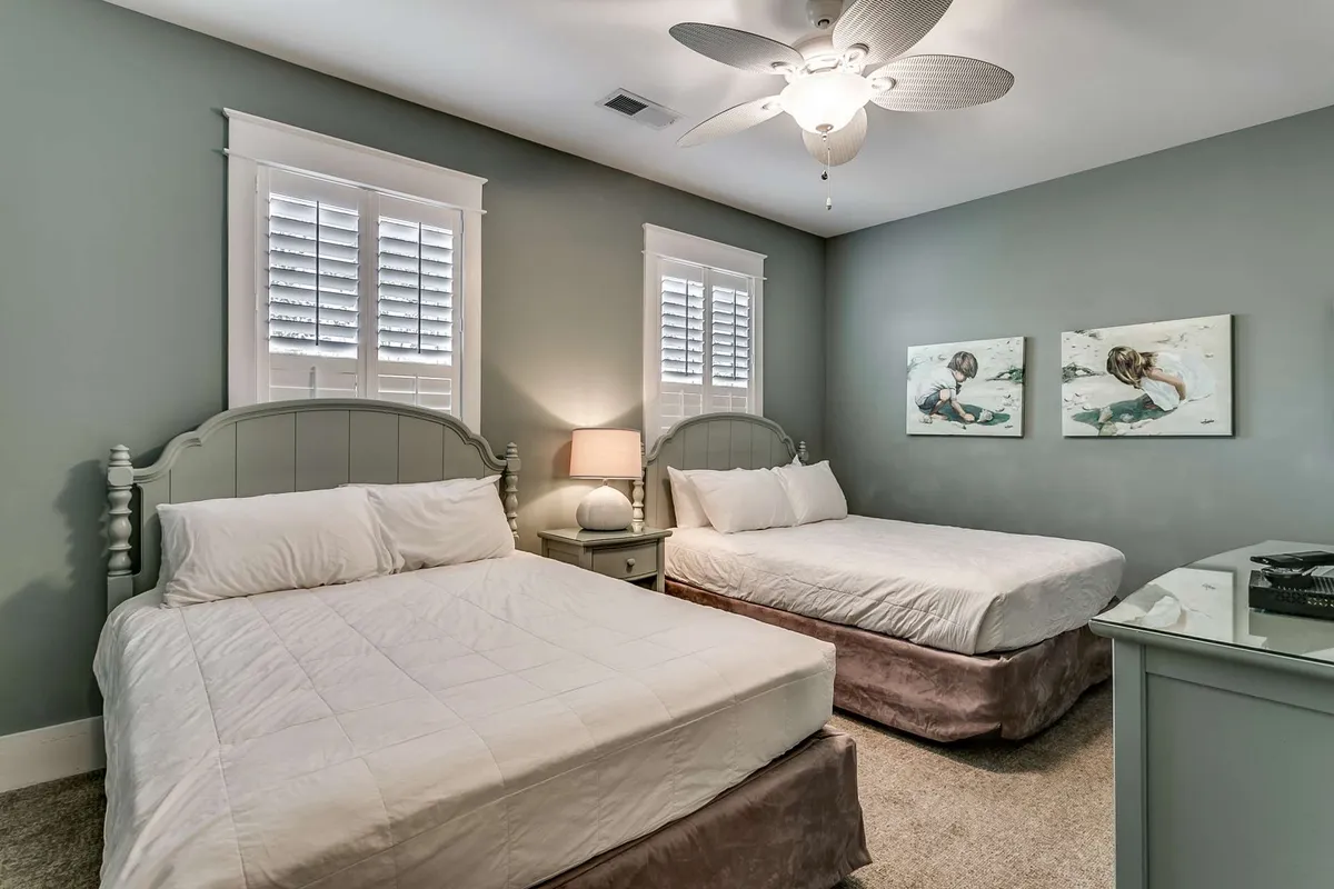 A comfortable, serene bedroom setup featuring two beds with soft linens and pillows, a nightstand with a lamp, and framed artwork on the walls. The inviting atmosphere is perfect for families, friends, or couples needing flexibility and privacy.