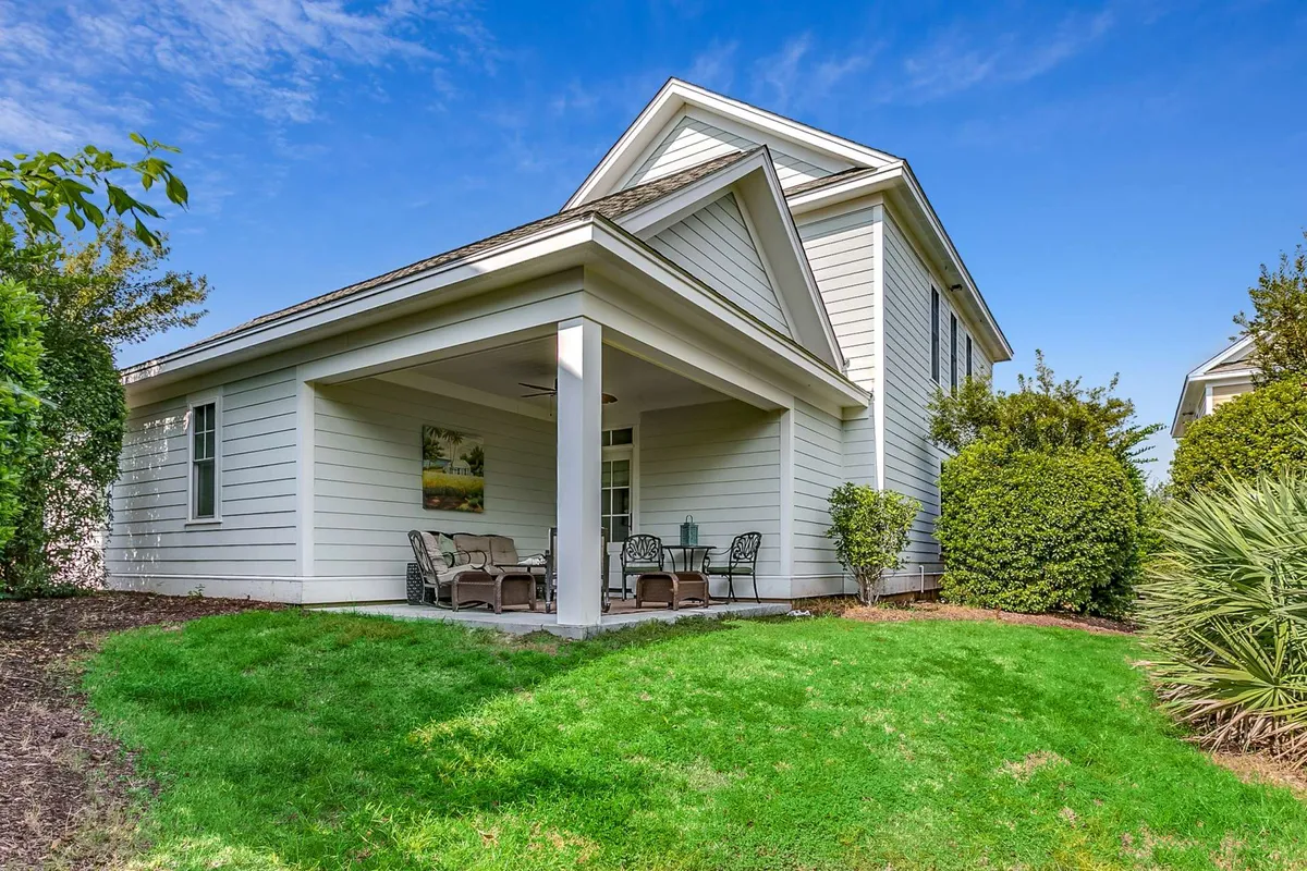 A serene porch area featuring comfortable seating, surrounded by lush green lawn and decorative plants. The scene conveys a peaceful, inviting outdoor living space perfect for relaxing, entertaining, or enjoying the view.